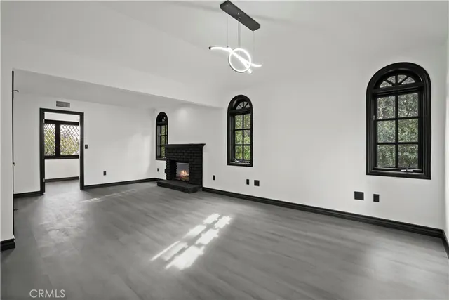 a view of an empty room with window and wooden floor