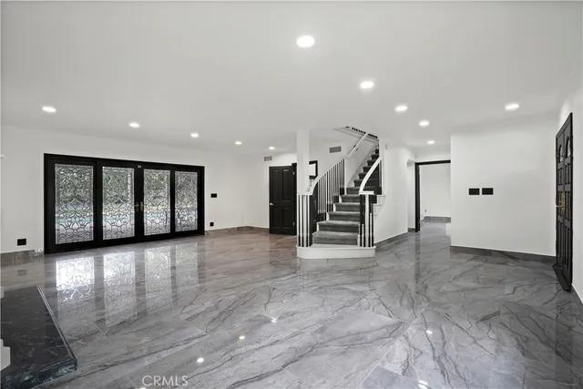 a view of an empty room with wooden floor and stairs