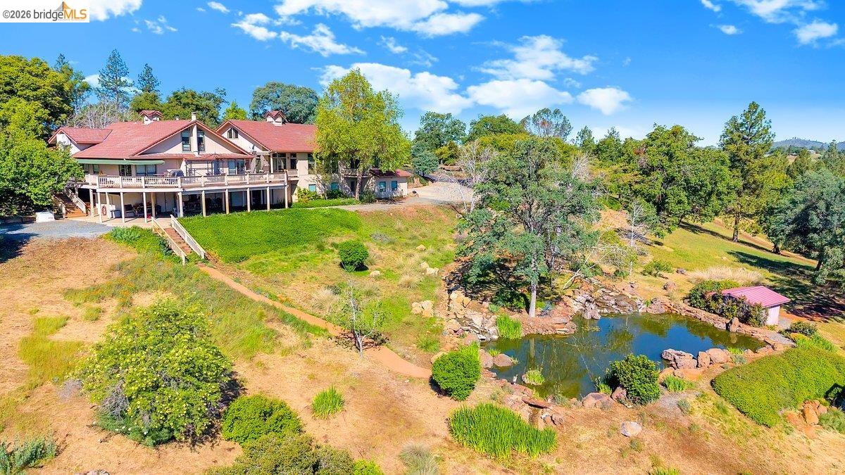13700 Clements Road Groveland, CA 95321 - Photo 86 of 93 Expansive property featuring a multi-level structure with a full-length upper deck, a lower covered patio, and a naturalistic pond with rock landscaping