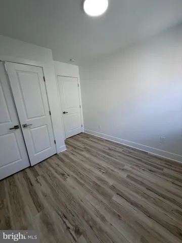 a view of an empty room with wooden floor and window
