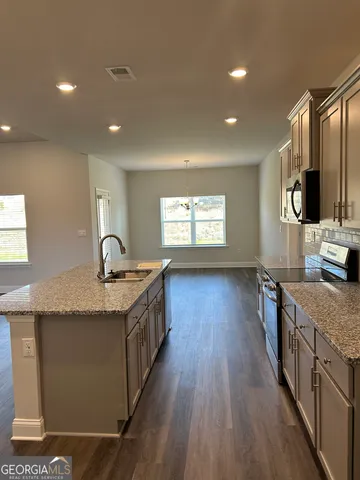 a kitchen with stainless steel appliances granite countertop a sink stove and wooden floor