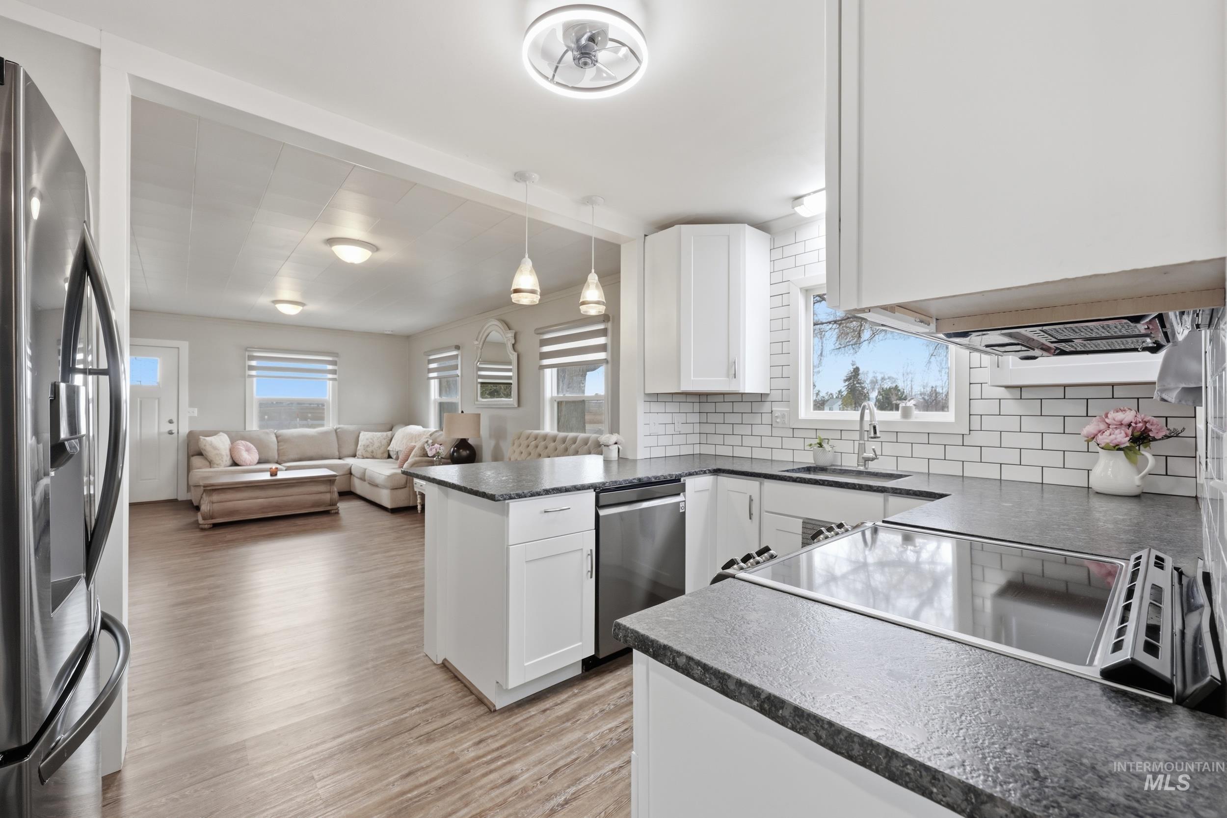 9762 Deer Flat Road Nampa, ID 83686 - Photo 24 of 24 Kitchen featuring dark countertops, open floor plan, stainless steel appliances, pendant lighting, and backsplash