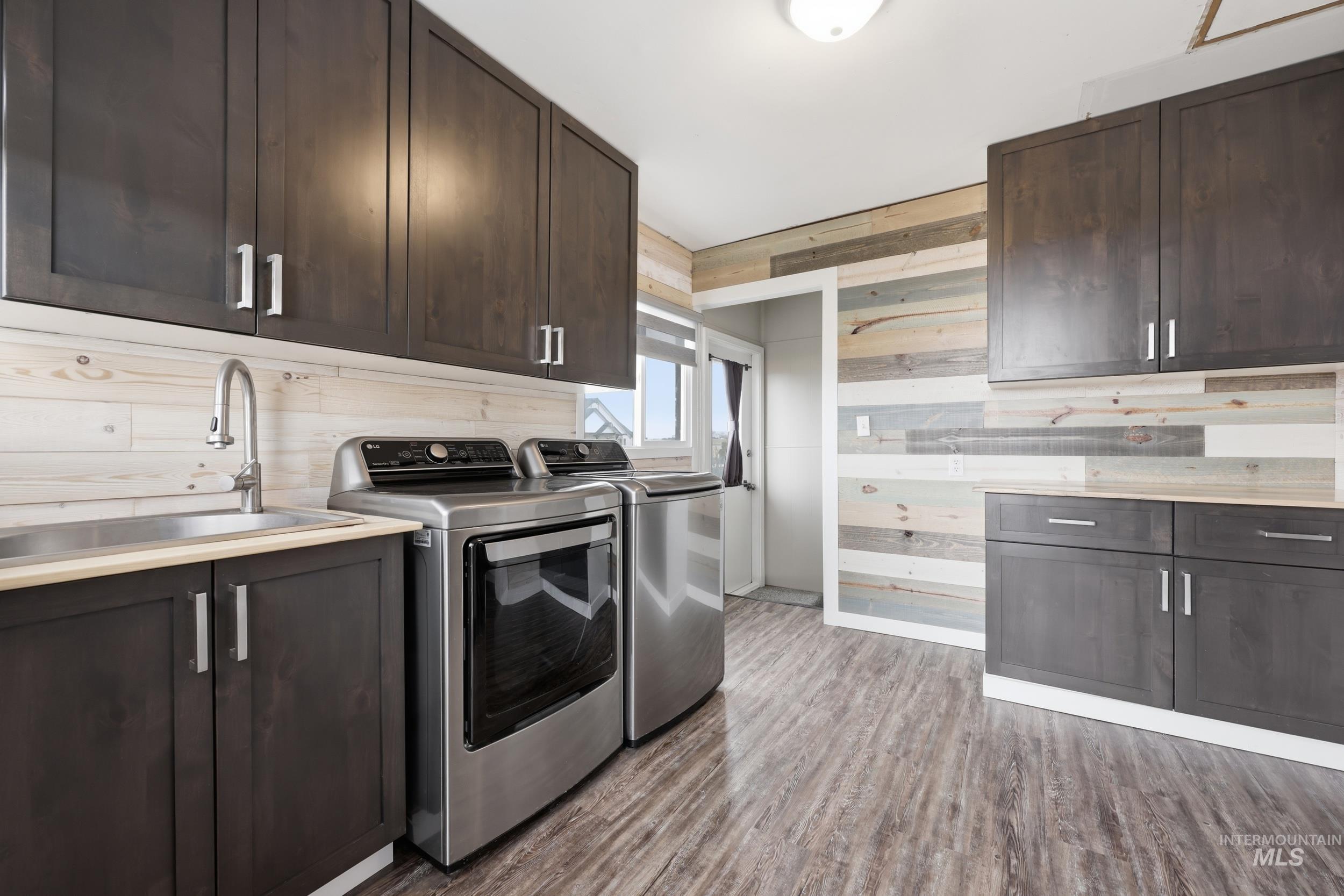 9762 Deer Flat Road Nampa, ID 83686 - Photo 8 of 24 Laundry area featuring cabinet space, wood walls, light wood-style floors, and separate washer and dryer