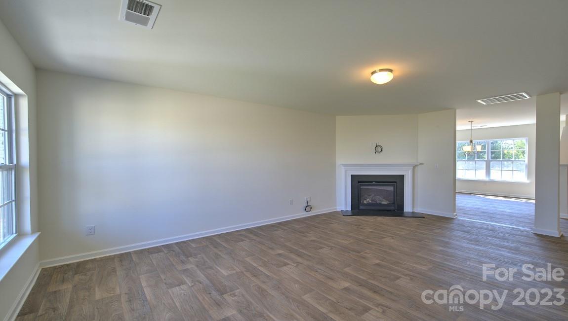 1374 Mifflin Lane Dallas, NC 28034 - Photo 3 of 20 an empty room with wooden floor a fireplace and windows