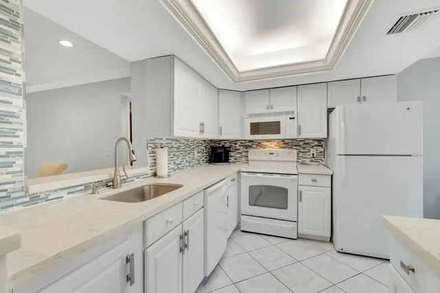 a kitchen with white cabinets and white appliances