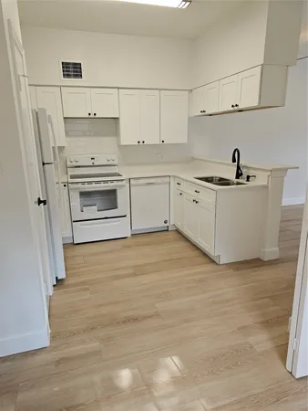 a kitchen with white cabinets and white appliances