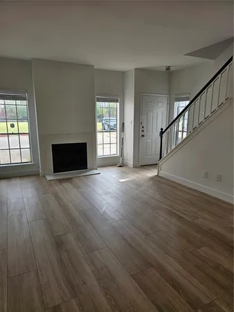 a view of an empty room with wooden floor fireplace and a window