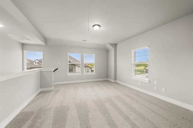 an empty room with wooden floor fireplace and windows