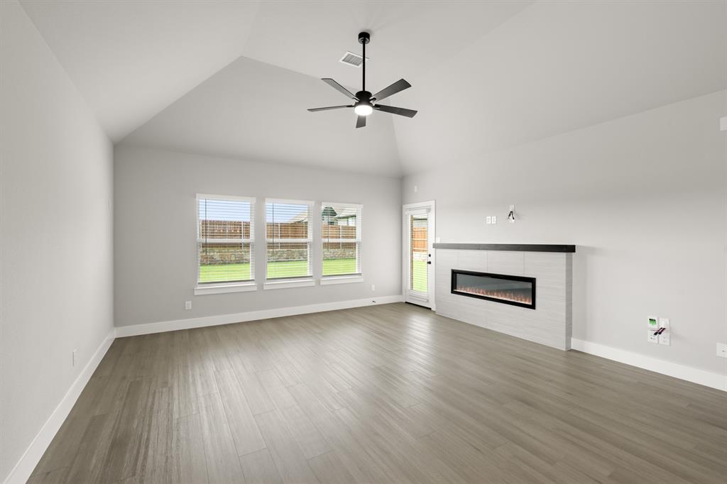 620 Red Maple Road Waxahachie, TX 75165 - Photo 25 of 40 an empty room with wooden floor fireplace and windows