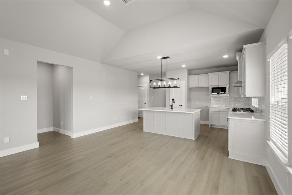 620 Red Maple Road Waxahachie, TX 75165 - Photo 6 of 40 a large white kitchen with kitchen island a sink wooden floor and stainless steel appliances
