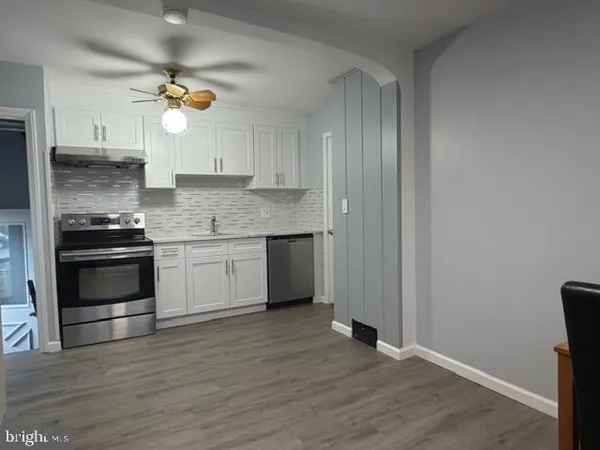 a kitchen with granite countertop white cabinets and stainless steel appliances