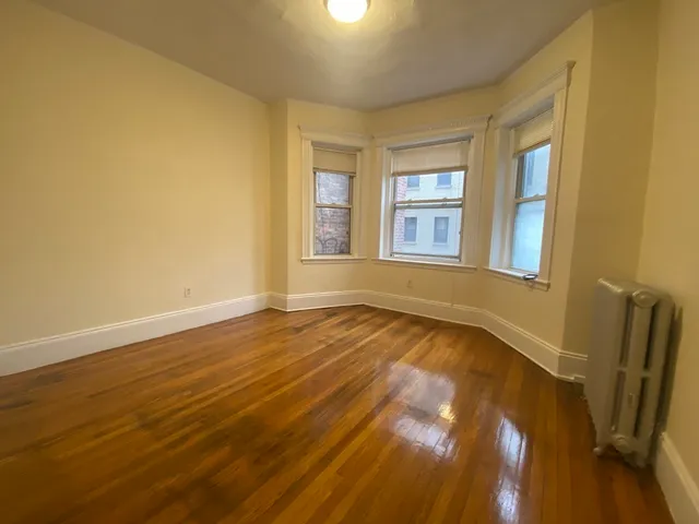 a view of an empty room with a window and wooden floor