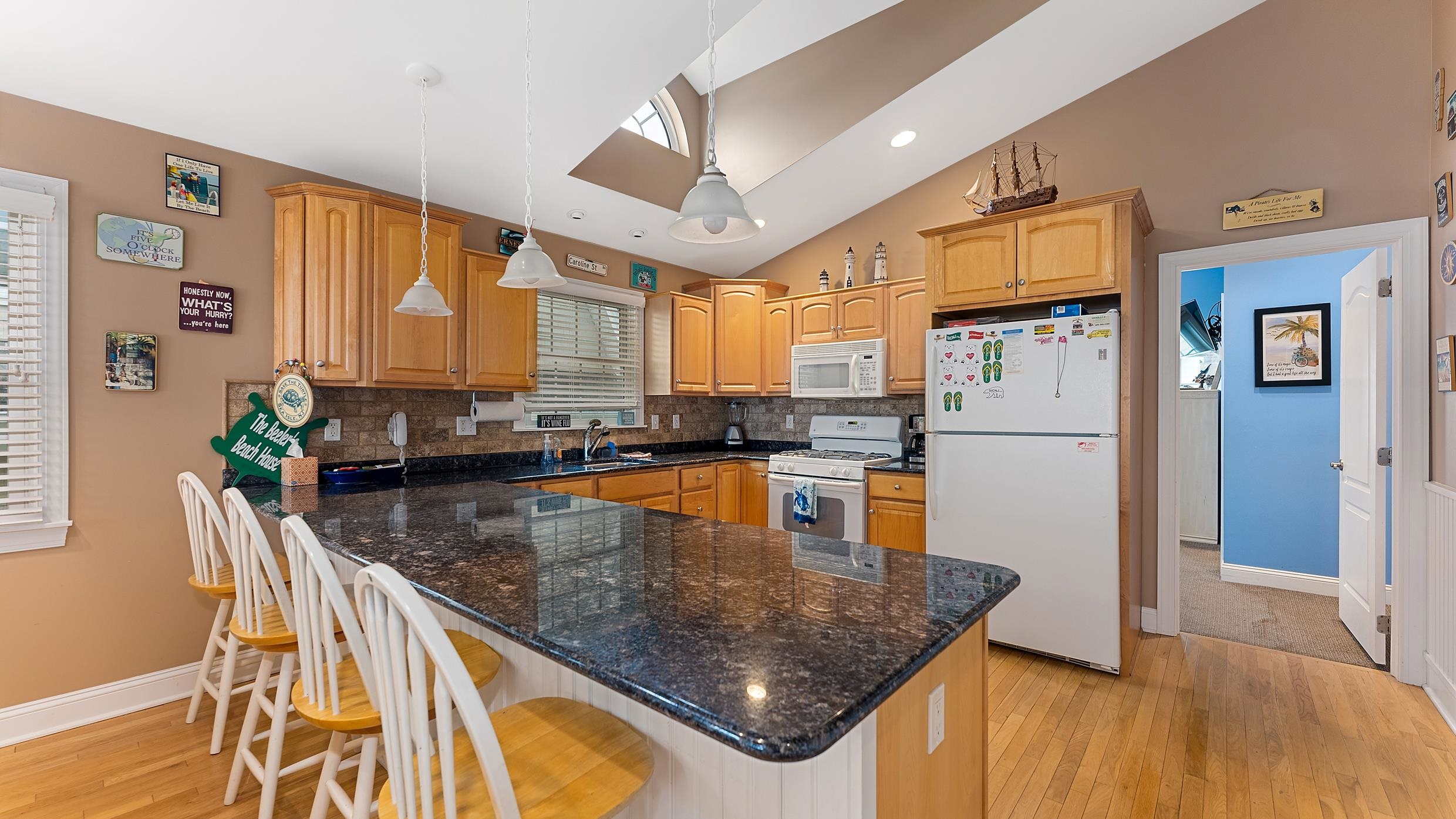9 78th Street, Unit WEST Sea Isle City, NJ 08243 - Photo 7 of 24 a kitchen with stainless steel appliances granite countertop a stove a refrigerator a oven a sink a dining table and chairs with wooden floor