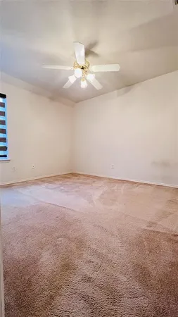 an empty room with windows and chandelier fan