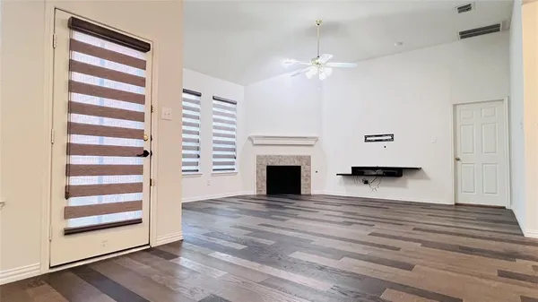 a view of a room with wooden floor fireplace and window