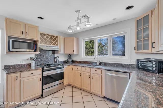 a kitchen with granite countertop stainless steel appliances a stove sink and microwave