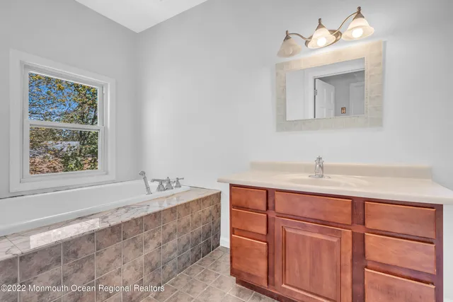 a bathroom with a tub sink and mirror