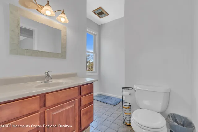 a bathroom with a granite countertop toilet sink and mirror