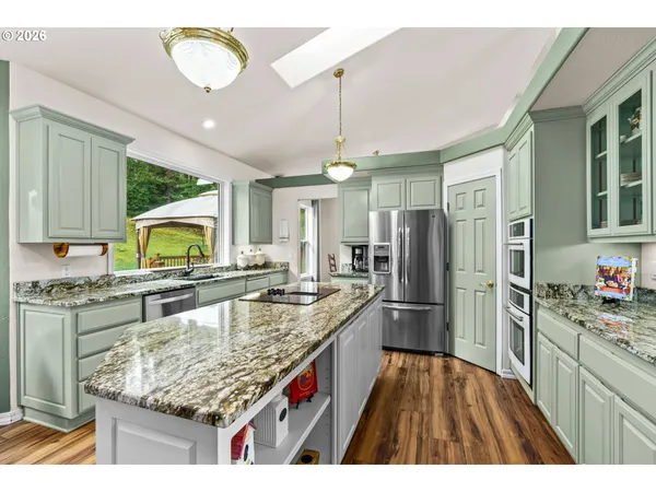 a kitchen with stainless steel appliances granite countertop a sink refrigerator and cabinets