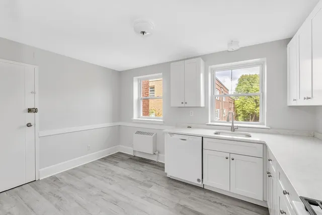 a view of cabinets a sink and dishwasher in a white room
