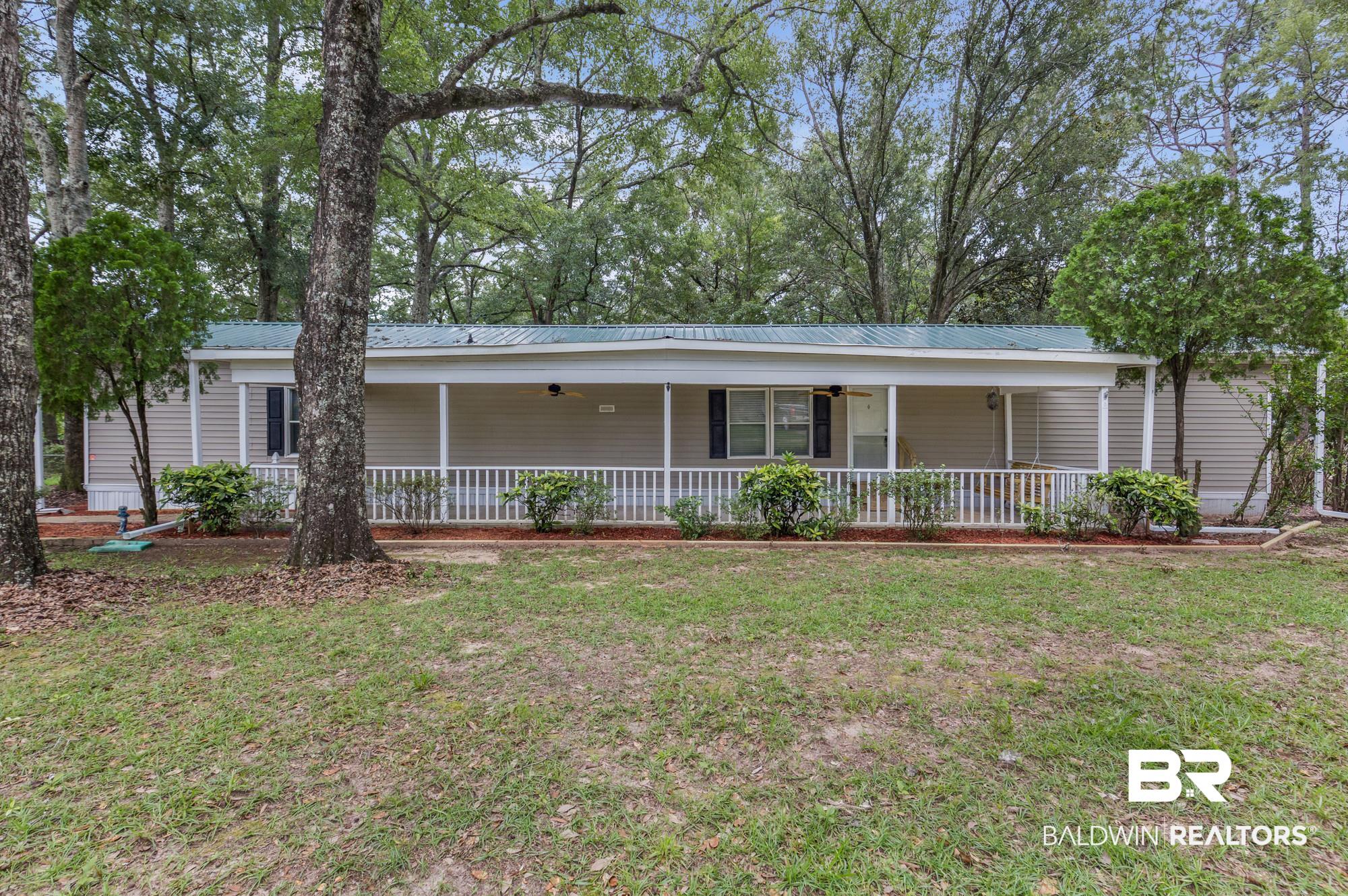 8675 Hunters Pointe Drive North Theodore, AL 36582 - Photo 2 of 20 Single-story residence featuring light-colored siding, a green metal roof, and a full-length covered front porch with white railing