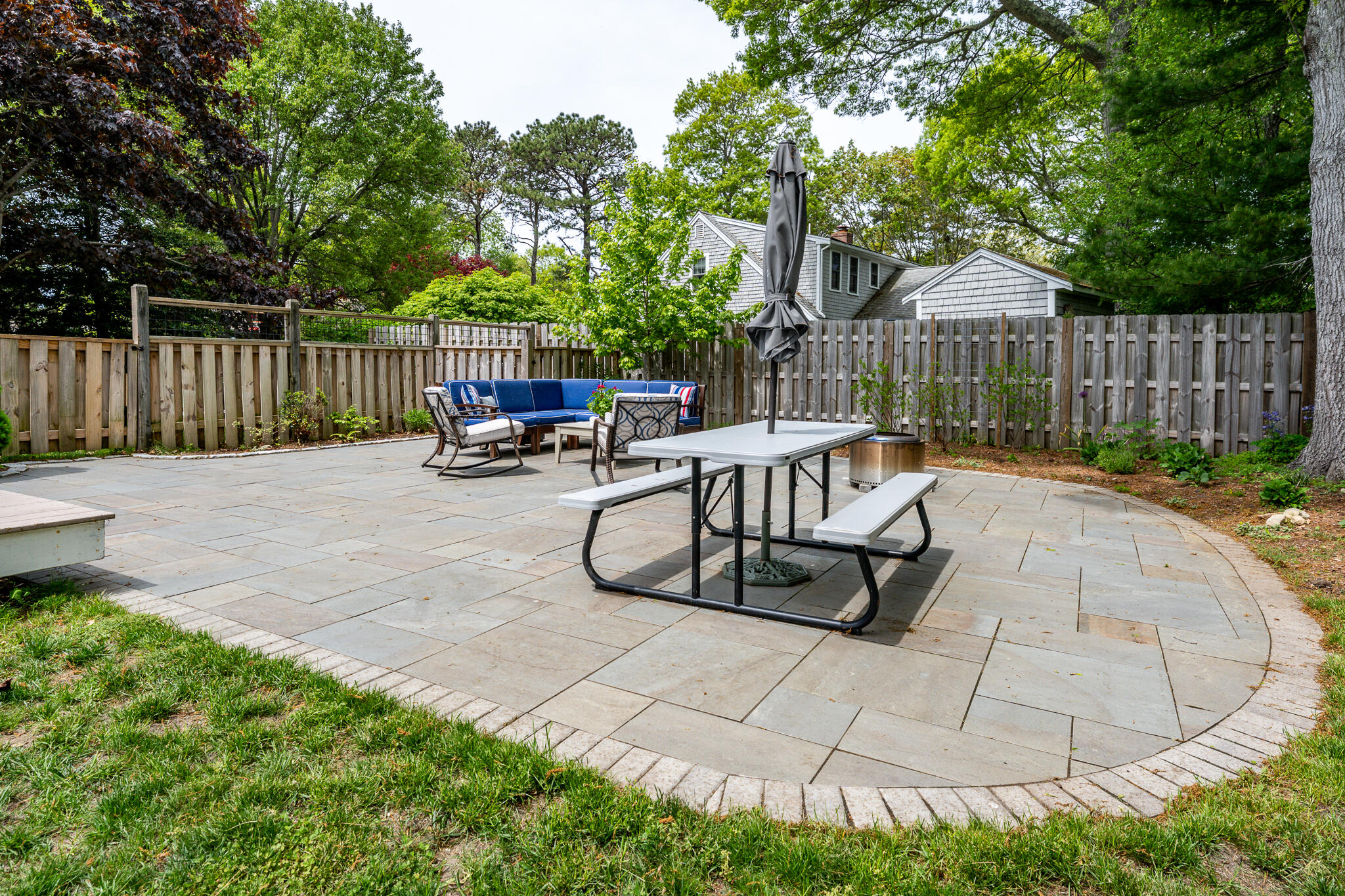 61 Angus Way Centerville, MA 02632 - Photo 46 of 59 a view of a patio with table and chairs potted plants and wooden fence
