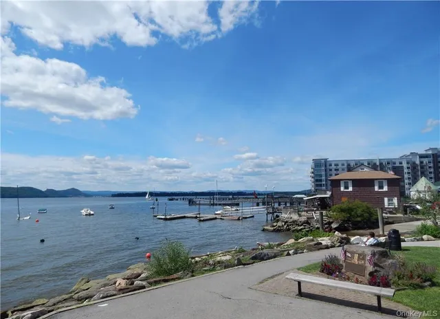 a view of road with card parked on side and retail shops
