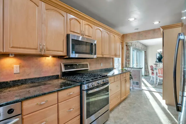 a kitchen with stainless steel appliances granite countertop a stove a sink and a microwave