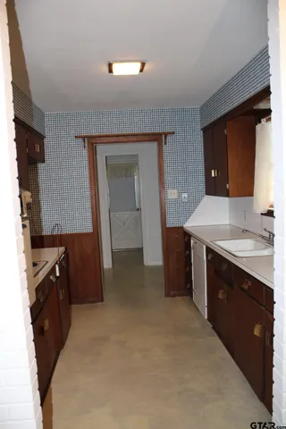 a kitchen with sink a refrigerator and wooden cabinets