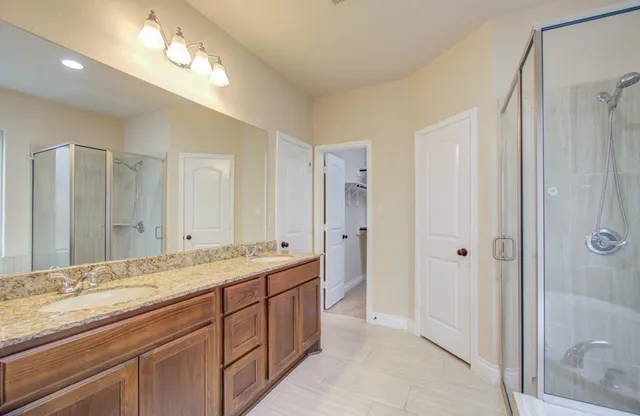 a spacious bathroom with a shower a sink and a mirror