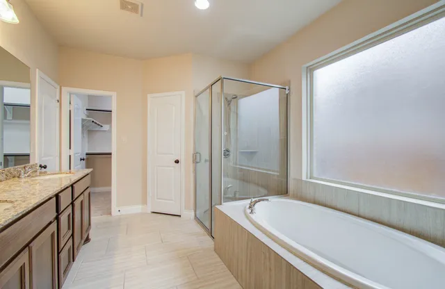 a bathroom with a granite countertop bathtub shower sink and mirror