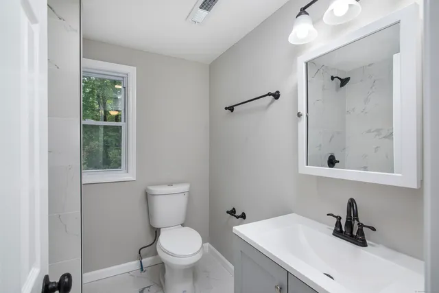 a bathroom with a sink a toilet and shower