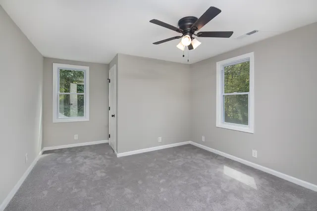 an empty room with windows and ceiling fan