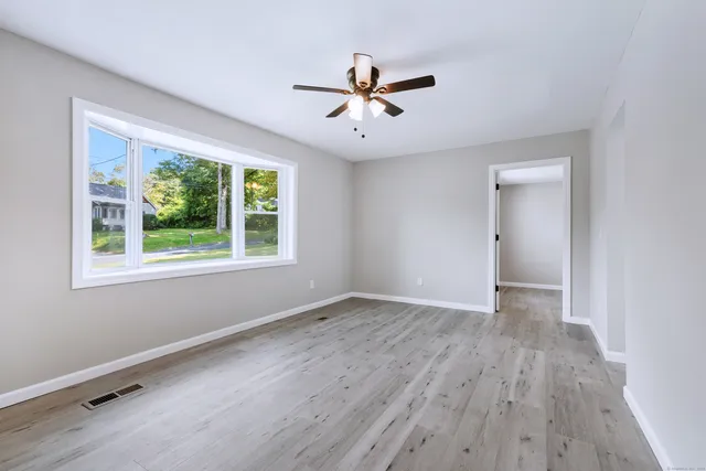 a view of an empty room with wooden floor and a window