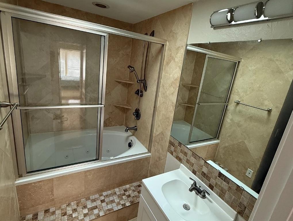 6505 Mc Cormick Ranch Court Plano, TX 75023 - Photo 19 of 21 Bathroom featuring a jetted tub, full-height tile surround, glass shower enclosure, and integrated corner shelving