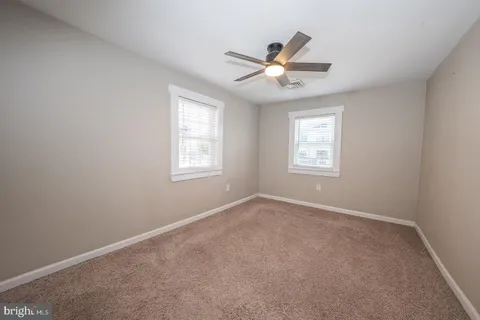 an empty room with windows and ceiling fan