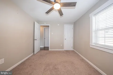 an empty room with chandelier fan and windows