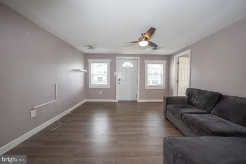 a living room with couches and potted plants with wooden floor