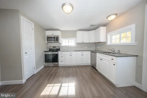 a kitchen with granite countertop a sink cabinets stainless steel appliances and a window