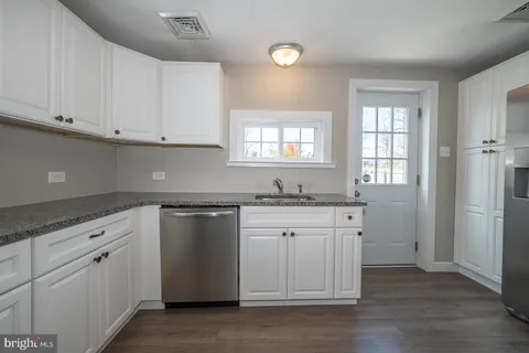 a kitchen with granite countertop white cabinets and a sink