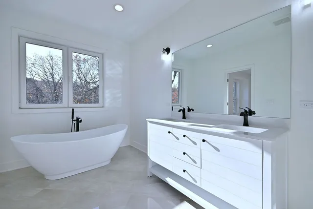 a spacious bathroom with a double vanity sink a mirror and a bathtub