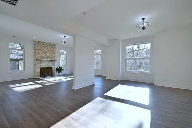 an empty room with wooden floor fireplace and windows