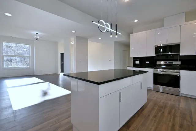 a kitchen with stainless steel appliances kitchen island granite countertop a sink a stove top oven a counter space and cabinets