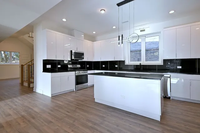 a large kitchen with stainless steel appliances granite countertop a stove a sink and white cabinets
