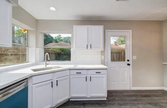 a view of a large kitchen with a large window cabinets and stainless steel appliances