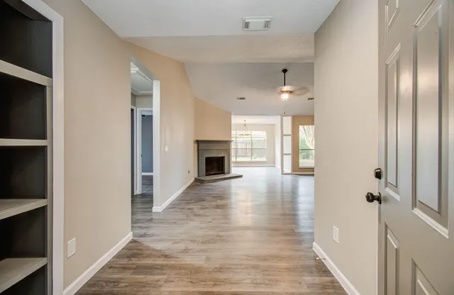 a view of a hallway with wooden floor and a kitchen