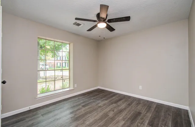an empty room with wooden floor a ceiling fan and closet