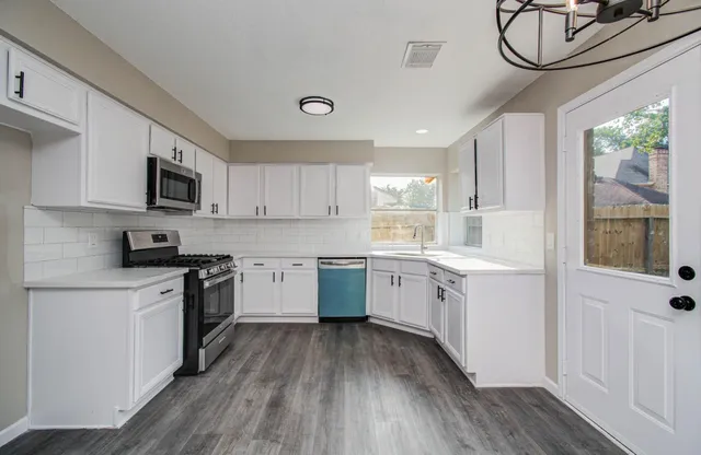 a kitchen with granite countertop white cabinets and stainless steel appliances