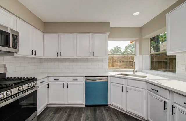 a kitchen with granite countertop a stove a sink and a refrigerator