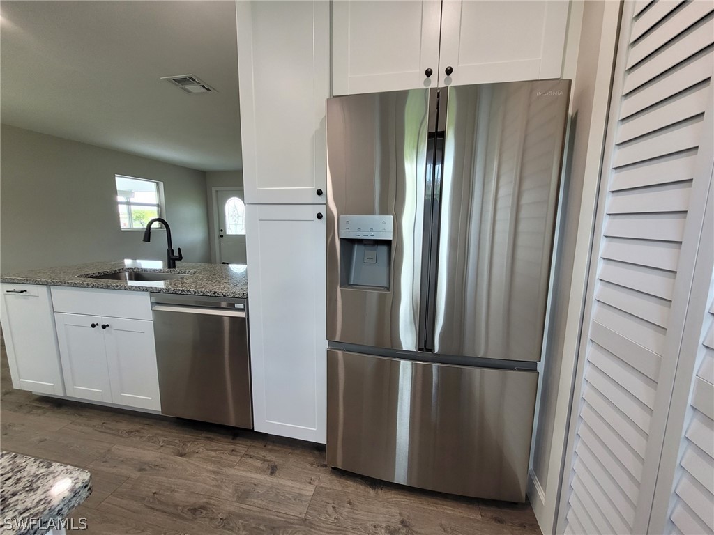 105 Alabama Road South Lehigh Acres, FL 33936 - Photo 14 of 25 a kitchen with stainless steel appliances granite countertop a refrigerator and a sink